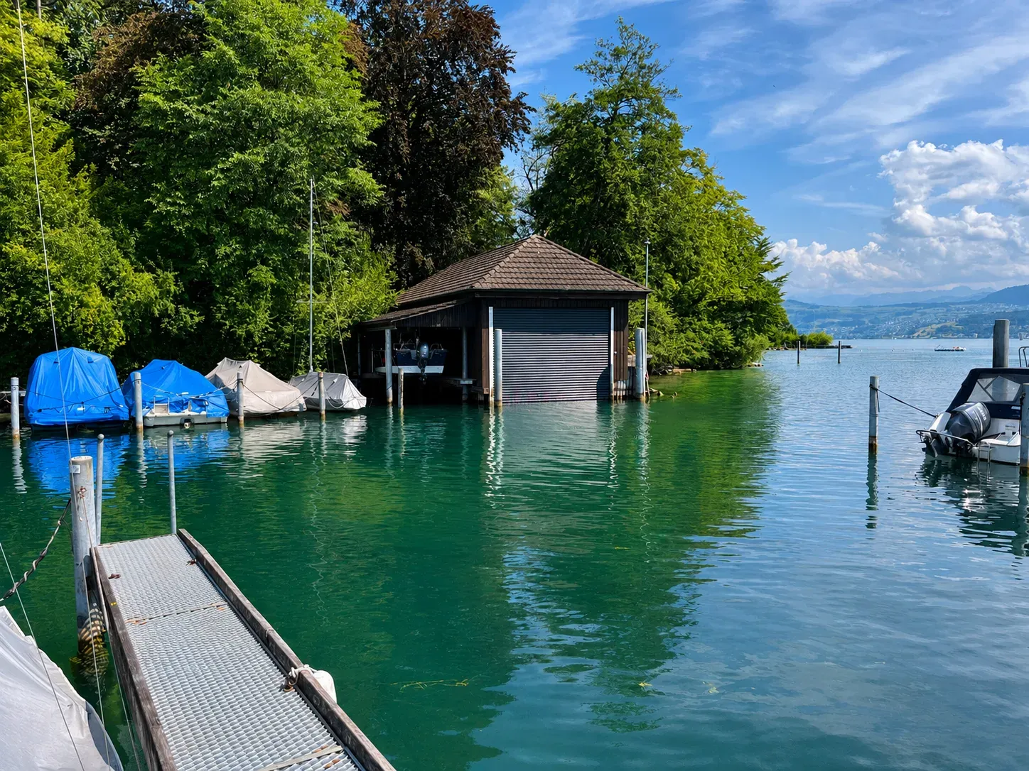 Bootshaus am Zürichsee in Meilen mit geschlossenem Spezialrolltor, davor Bootsstege und vertäute Boote