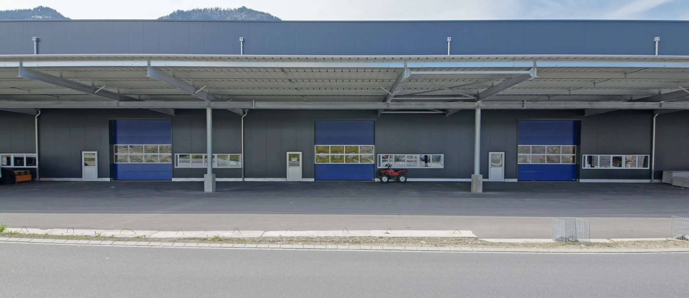 Drei blaue Sektionaltore unter dem Vordach der Gewerbehallen Gläntern in Reichenburg