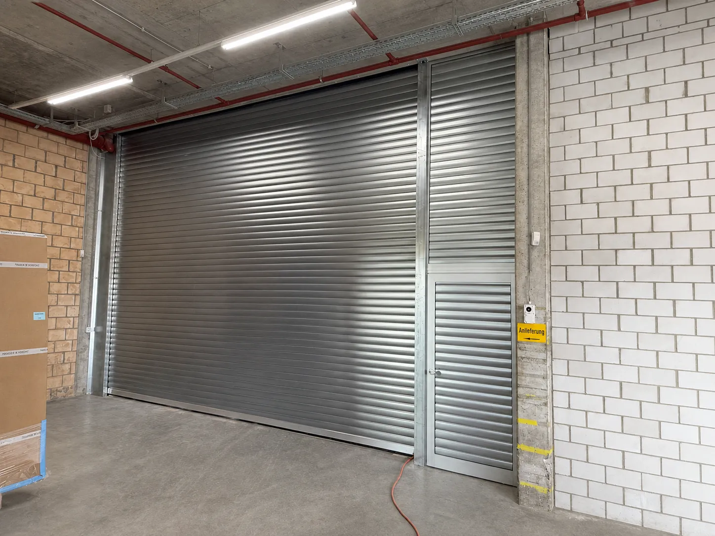 Rolltor STP-RT-60 mit separater Nebentür und Metall-Unterkonstruktion bei Kraft E.L.S. AG in Effretikon