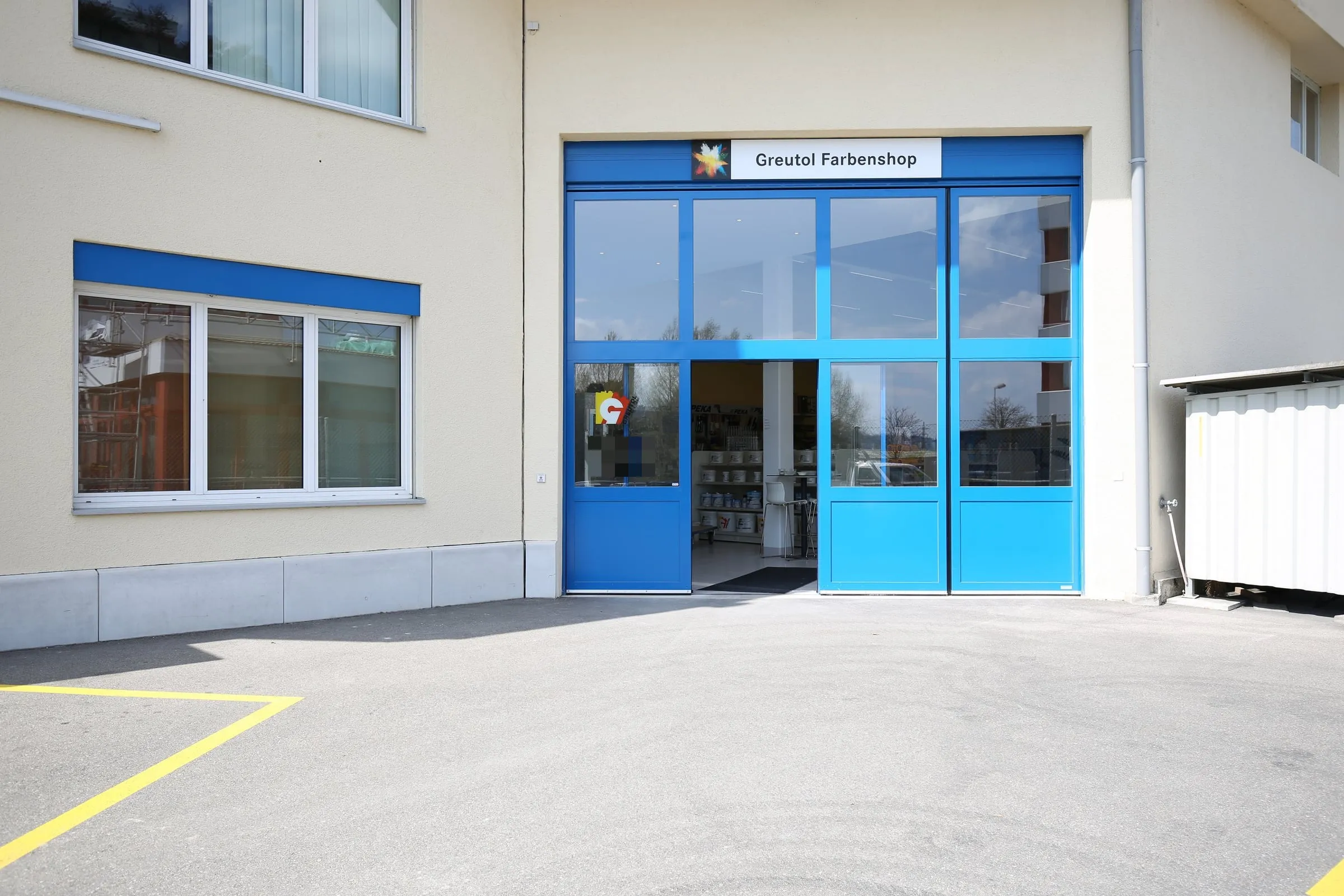 Blaue verglaste Tor- und Ladeneingangsfront am Greutol-Farbenshop in Otelfingen