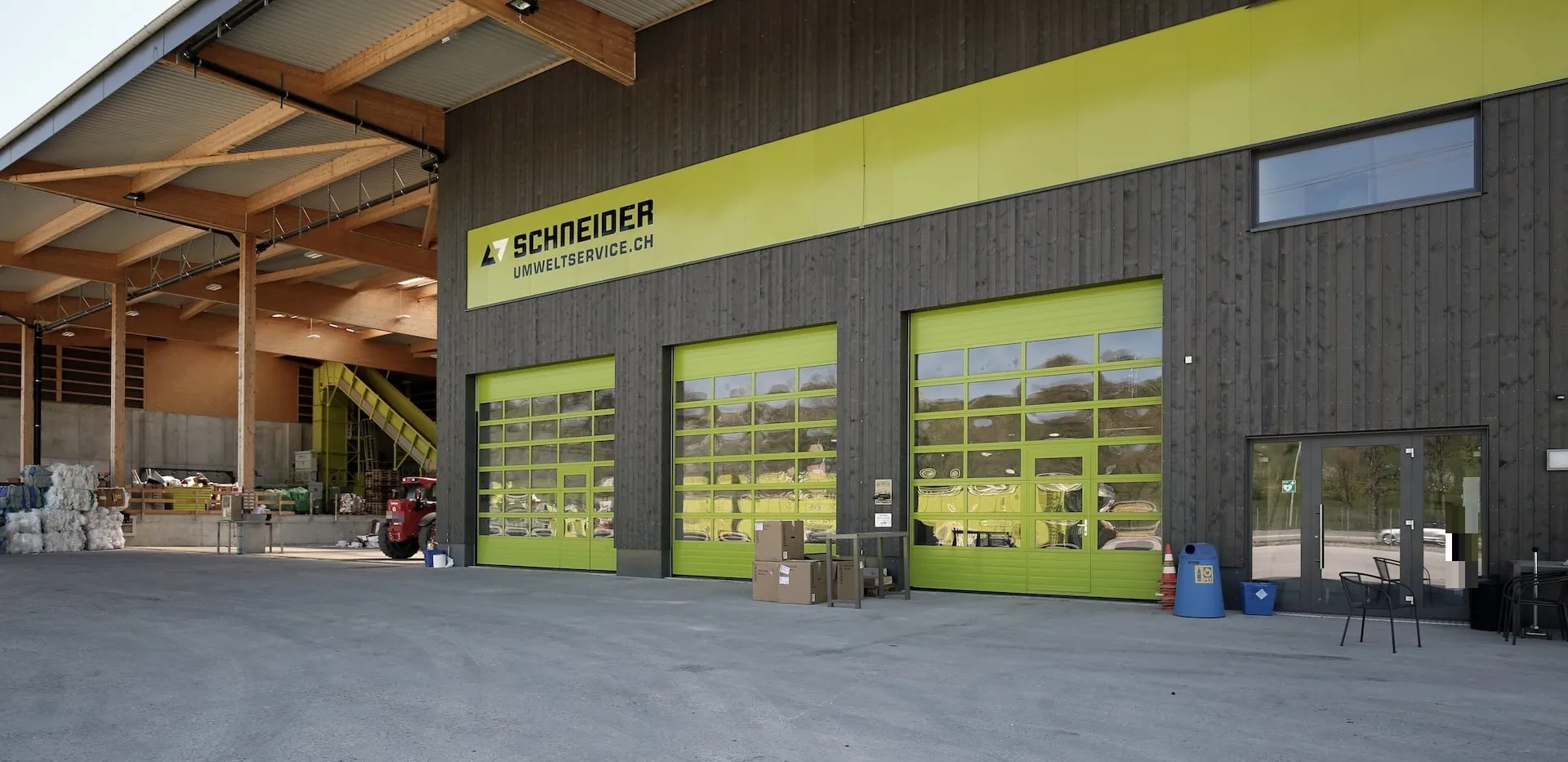 Schrägansicht der lemonfarbenen Sektionaltore unter dem Holz-Vordach, Schneider Umweltservice Volketswil