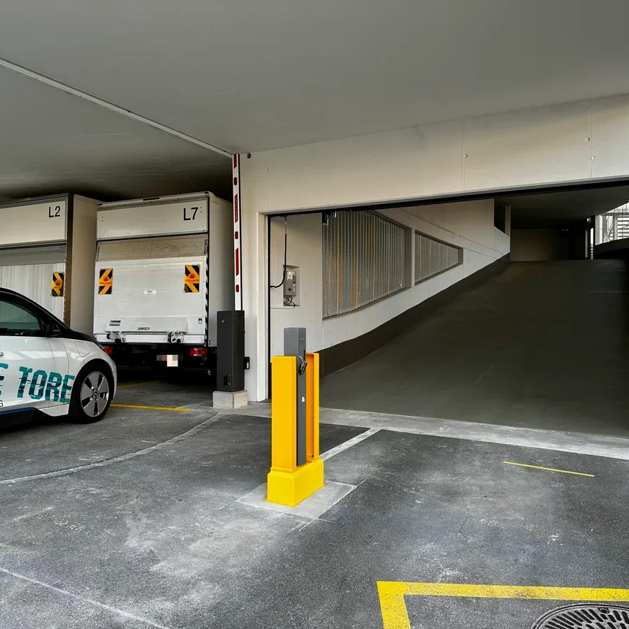 Parkhauszufahrt mit zwei geöffneten Parkschranken und Servicefahrzeug von Staub + Partner